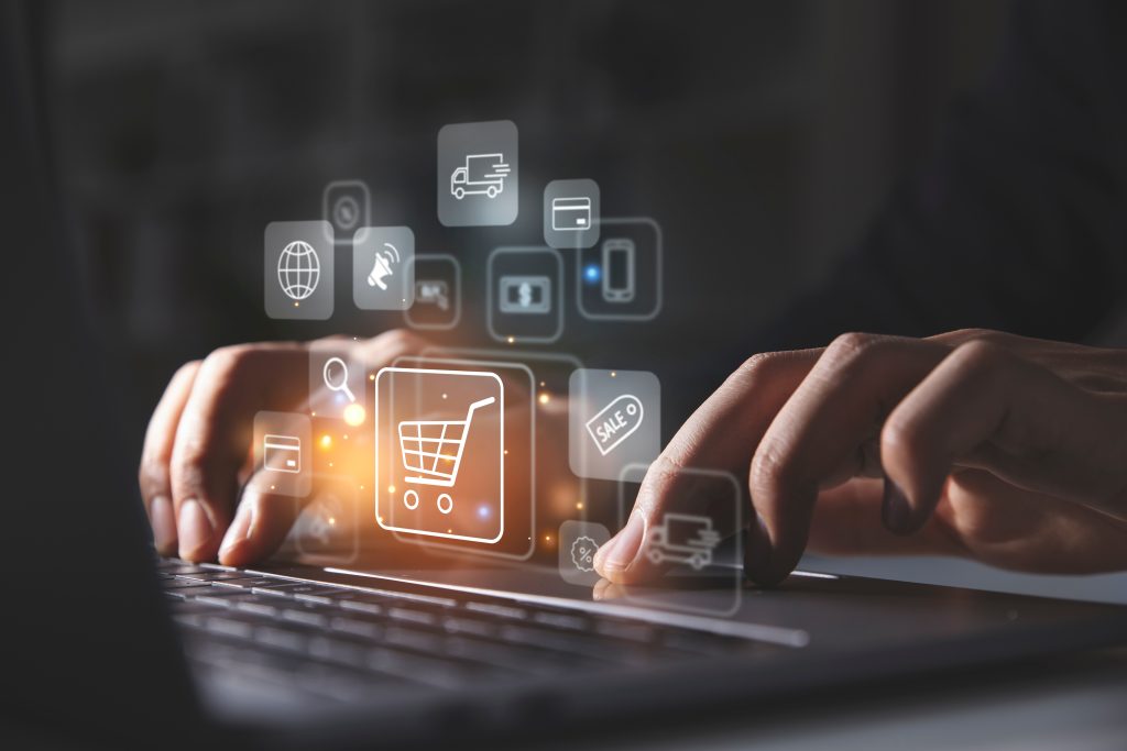 fingers on laptiop keyboard with e-commerce images floating above